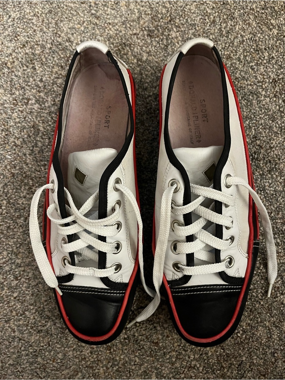 Donald J Pliner white canvas and black leather sneakers with red trim.